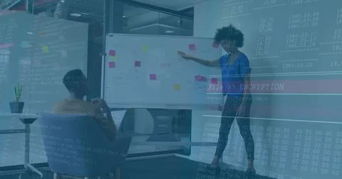 Pointing presenter in patterned pants at whiteboard in office with laptop, code 写真素材