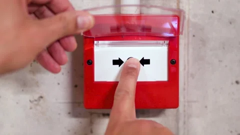 Pointing at red fire alarm switch on concrete wall in o Stock-Footage 231033132