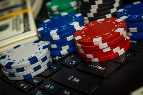 Poker chips and packs of dollars on a laptop keyboard Stock Photos