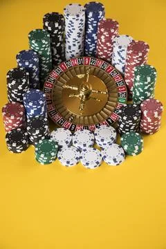 Poker Chips on gaming table, roulette wheel in motion, casino background Stock Photos