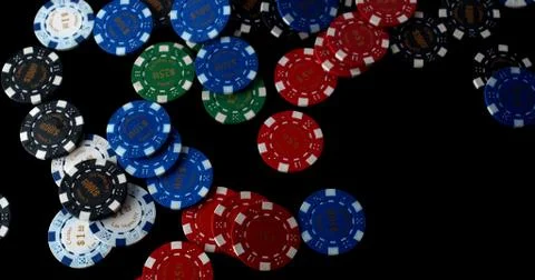 Poker chips of multiple colours sprawled across a black table top Stock Photos