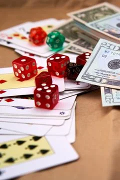 Poker deck spread out on a table with a pile of different dice and dollars. Stock Photos