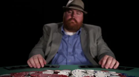 Poker player plays with chips in the pot as he laughs maniacally over them Stock Footage 53245285