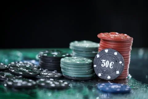 Poker playing chips on a green table and black background under the water drops. Stock Photos