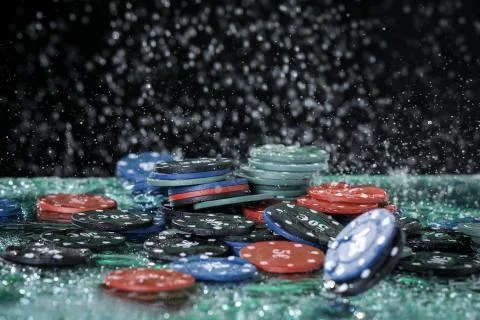 Poker playing chips on a green table and black background under the water drops. Stock Photos