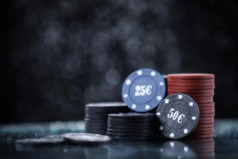 Poker playing chips on a reflected table and black background. Online gambling. Stock Photos