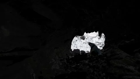 Polar bear sits in dark cave with snowy mountain outside. Stock Footage 266652155