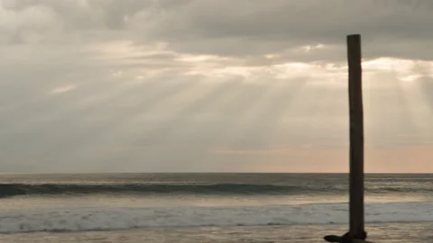 Pole on the beach by the ocean with sun rays through the clouds Stock Footage 217430923