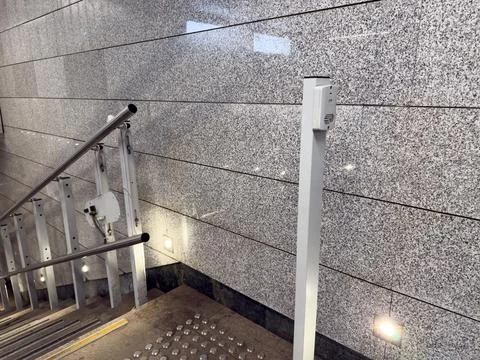 Pole with button in underground passageway to activate elevator on stairs. Pl Fotos de archivo