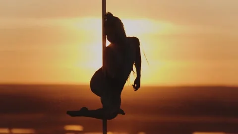Pole dance on bright sunset - acrobatic woman spinning on the dancing pole Stock Footage 136558801