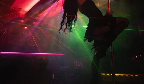 Pole dancer performing under laser lights in club. Stock Photos