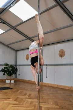 Pole dancer in vertical format in a clear studio doing exercises Stock Photos