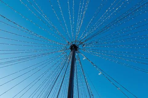 Pole with radiating string lights against clear blue sky Stockfoto's