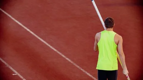 Pole vault training on the stadium - man in yellow shirt holding a pole Foto stock