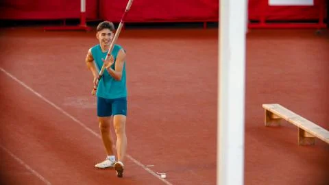 Pole vault training on the stadium - a young smiling man preparing before the Foto stock