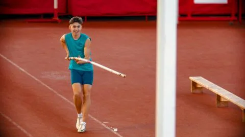 Pole vault training on the stadium - a young man in blue shirt preparing before Foto stock