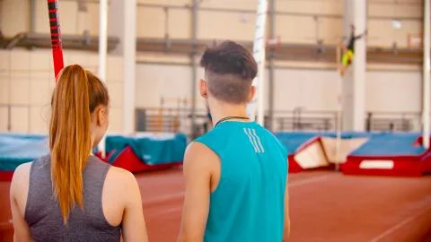 Pole vault training - young man and woman standing on the stadium and looking at Foto stock