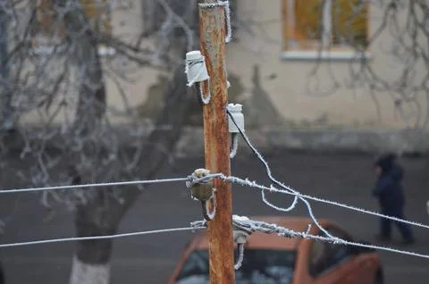 A pole with a wire on it is covered in ice.  Stock Photos