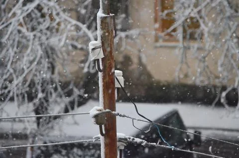A pole with a wire on it is covered in snow.  Stock Photos