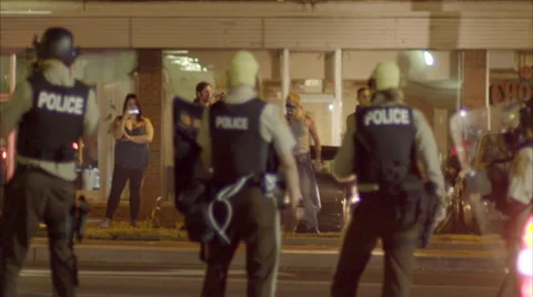 Police with automatic weapons patrol the streets during the Ferguson riots. Stock Footage