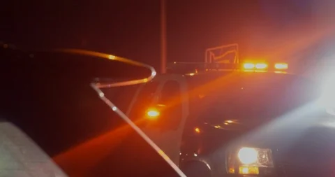 Police car with lights on pulling over car in foreground Stock Footage 94840749