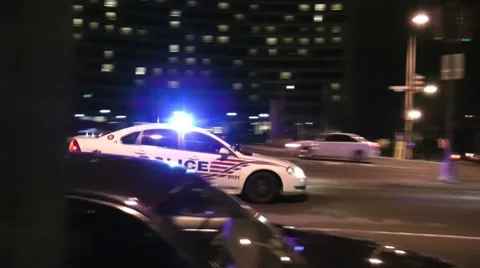 Police car races down city street, DC, night Stock Footage
