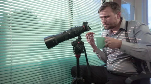 Police detective drinks coffee, eats pizza and watches through window blinds Vídeo Stock 97687049