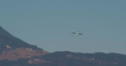 Police helicopter flying in front of massive and majestic mountains Stock Footage 171762204