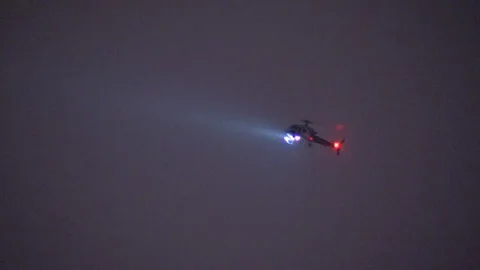 Police helicopter flying at night with flashing spotlight Stock Footage