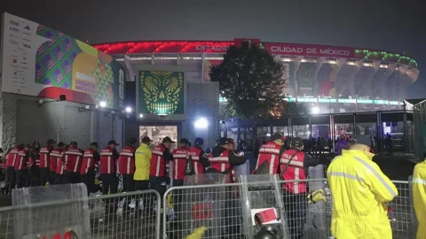 Police in high-visibility jackets behind barriers outside the stadium at night Stock-Footage 345278478