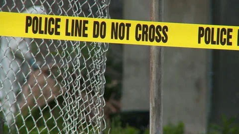 "Police Line Do Not Cross" tape with CSI removing evidence from crime scene. Vídeo Stock 108338663