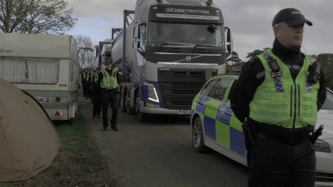 Police lines escorting heavy goods vehicles delivering to a fracking site, UK Stock Footage 82275641