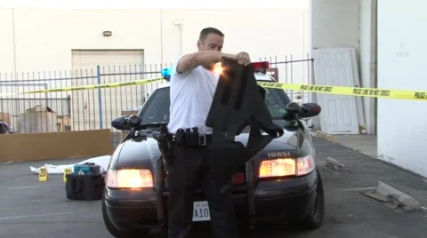 Police man models Bullet Proof vest with Cop car in background.mp4 Video stock 52003588