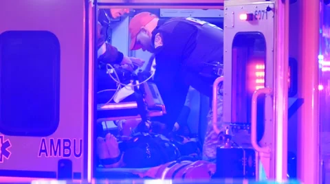 Police officer doing chest compression CPR in back of ambulance at night Stock Footage 43312456