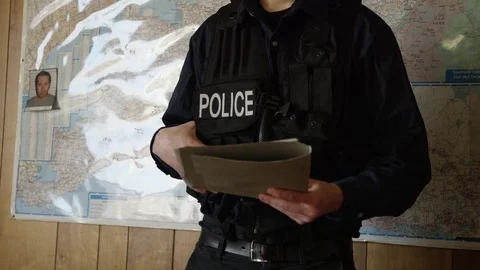 Police officer with file in front of a map Stock Footage 72974598