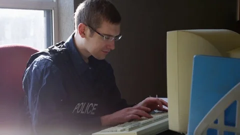 Police officer side profile doing paperwork on vintage computer Stock Footage 72760314