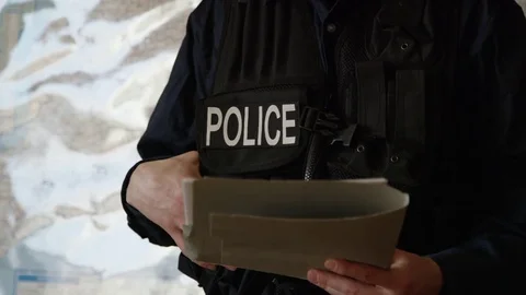 Police officer studying a file in front of a map Stock Footage 72974095