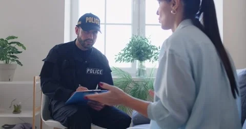 Police officer taking notes while interviewing emotional woman who was witness Stock Footage 317331606