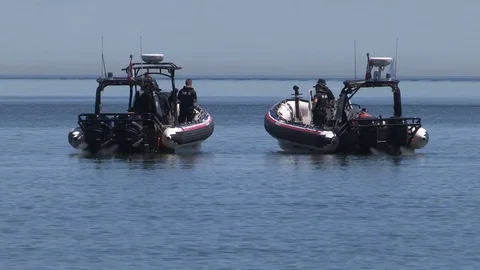 Police officers on boats at crime scene with dead body floating in lake Stock Footage