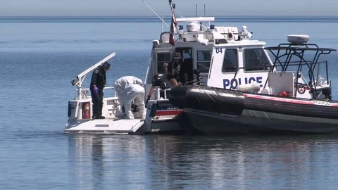 Police officers on boats at crime scene after dead body found floating in lake Stock Footage