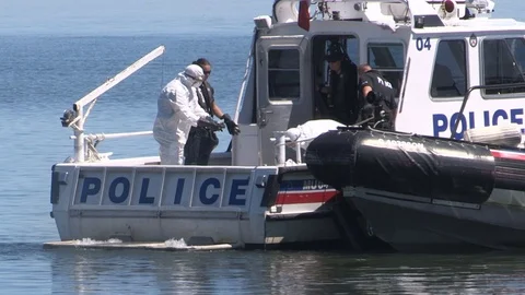 Police officers on boats at crime scene after dead body found floating in lake Stock Footage