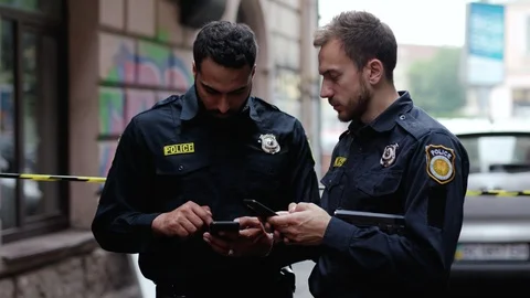 Police at raid. Close-up two handsome policemen searching on smartphones Video stock 112980743