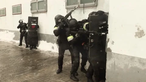 A police squad conducts combat exercises near the building using automatic Stock Footage 179864650