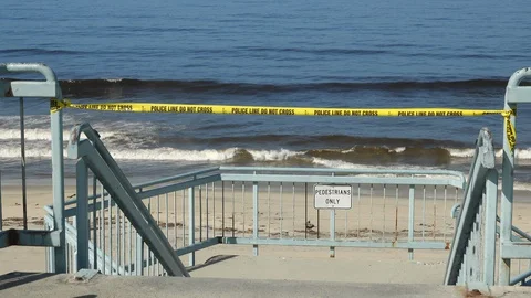Police tape blocks access to a beach closed due to Covid-19. Stock Footage 129581900