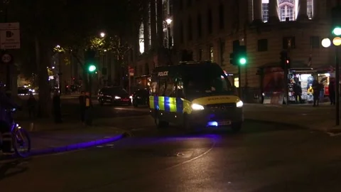 Police van on blue lights driving in London at night filmed in slow motion Stock Footage 223219322