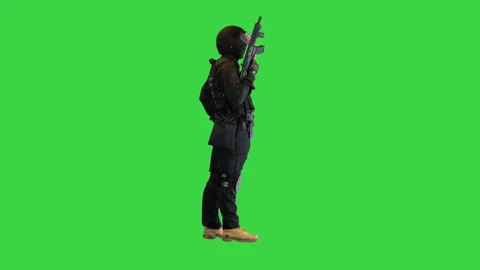 Policeman in protective cask with a rifle raised up on a Green Screen, Chroma 動画素材 149358939
