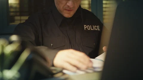 Policeman reviewing criminal case documents while answering a phone call Stock Footage 336853855