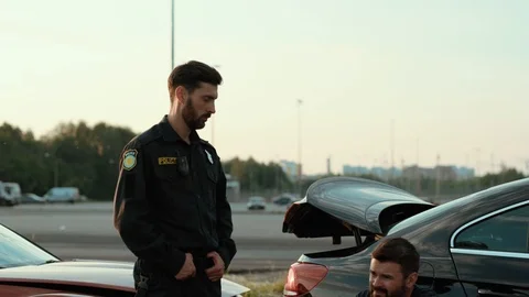 Policeman talking with a disappointed driver leaning on the crashed car. car Stock Footage 112988943
