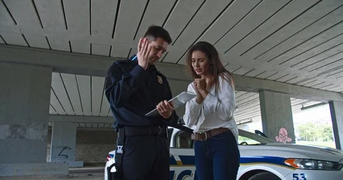 Policeman talks and questions young woman victim of crime outdoors. Close-up Stock Footage 112952677