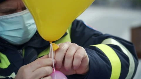 Policeman tying a balloon with a string Stock Footage 157629980